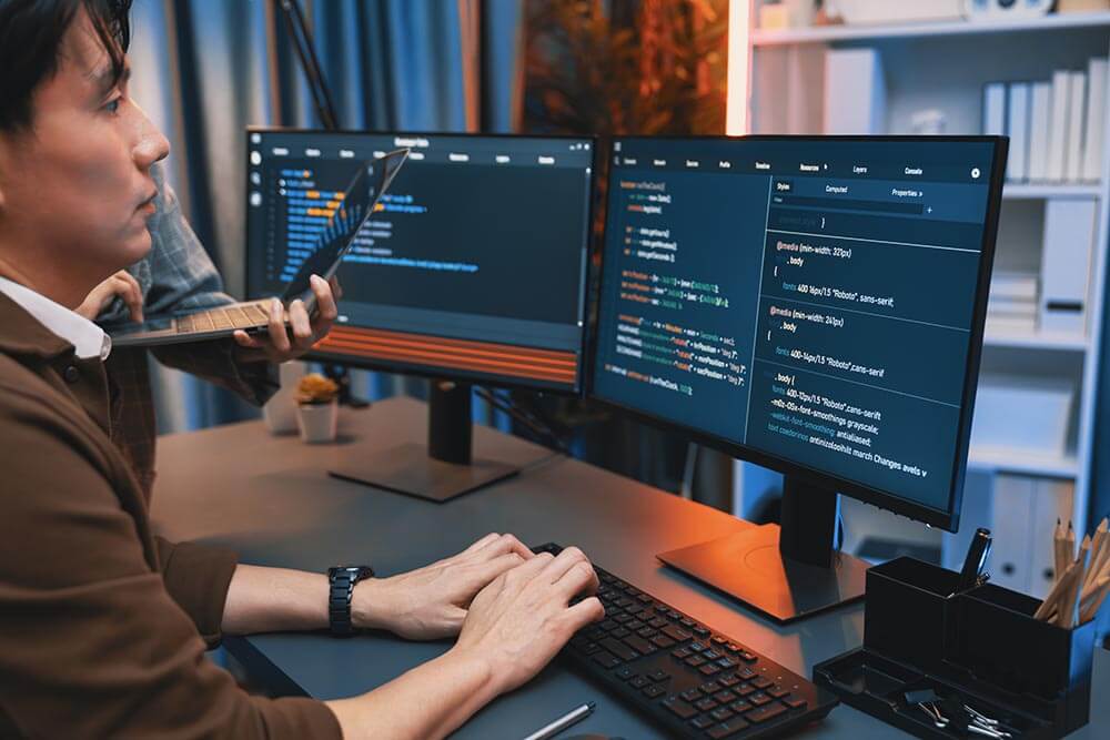 Developer coding on dual monitors