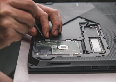 close up of repairmans hands removing hard drive from laptop case